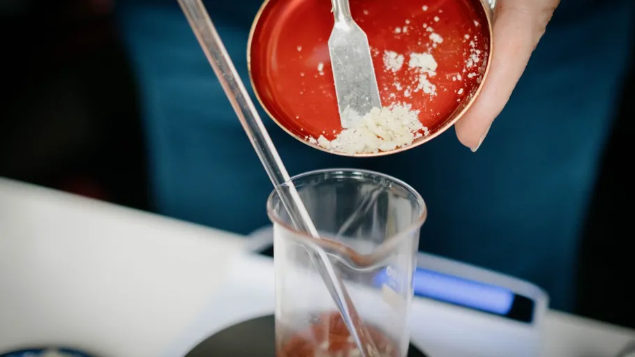 A spoonful of powder is poured into a glass.