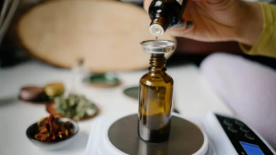 Braune Flasche wird mit Flüssigkeit gefüllt, auf einer Waage.