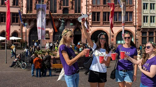 Vier Frauen feiern mit Getränken auf einem Platz.