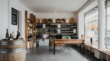 Wine shop with shelves, tables and bottles in the room.