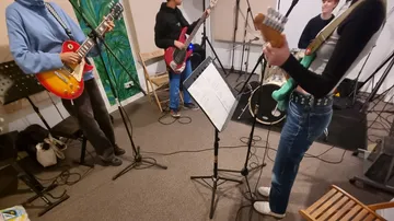 Music band rehearsing with guitars and music stand in studio.