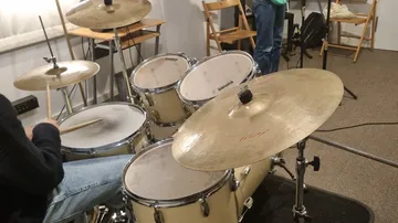Drums are played in a practice room with sticks.