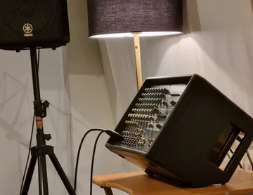 The mixer table stands diagonally on a wooden base next to a loudspeaker.