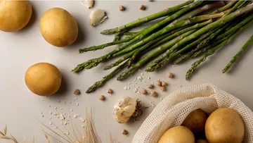 Potatoes and asparagus lie on a bright background.