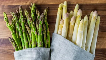 Grüner und weißer Spargel liegen auf einem Holzbrett.