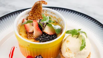 Dessert in gelbem Becher, garniert mit Früchten und Minze.