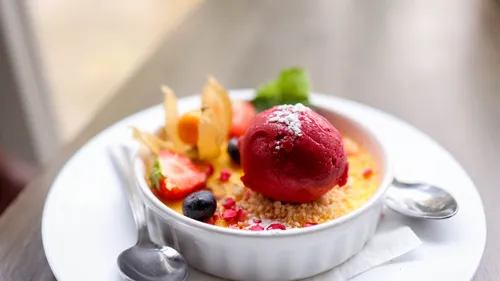 Dessert with sorbet, fruit and colorful topping in bowl.