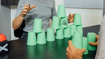 Green cups are stacked while players focus on them.
