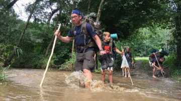 Hikers cross a flowing stream in nature.