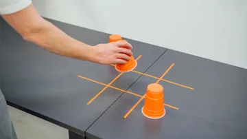 Orangene Becher werden auf einem Tisch in einem Spiel platziert.