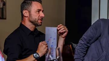 Man holds paper and talks in good company.