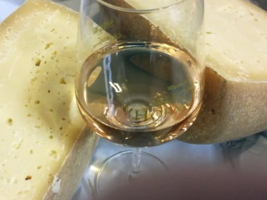 Käse und ein Glas Roséwein auf einem Tisch.