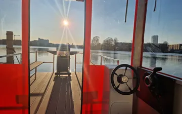 Ein Boot mit Grill und Steuerrad am Wasser.
