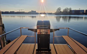 Barbecue is on a waterfront terrace at sunrise.