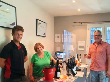 Wine tasting with three people in a bright room.