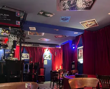 A bar with red curtains and pictures on the ceiling.