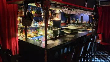 Eine Bar präsentiert alkoholische Getränke vor rotem Vorhang.