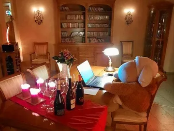 Plüschhase sitzt am Tisch vor einem Laptop in einem Zimmer.