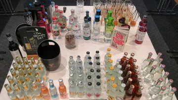 Bottles and glasses on table, ingredients prepared for cocktails.