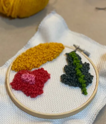Embroidered floral designs in an embroidery frame on fabric.