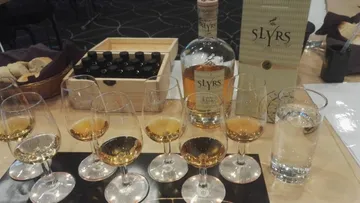 Gläser mit Whiskey stehen auf einem Tisch neben Wasser.