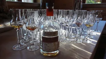 A bottle of spirit is placed between many glasses on the table.