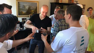 A person pours drinks in a friendly atmosphere.