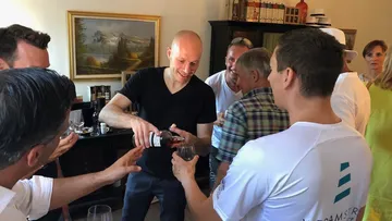 Ein Mann schenkt Getränke in einer geselligen Runde aus.