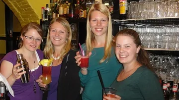 Vier Frauen halten Getränke in einer Bar. Freude, gesellig.
