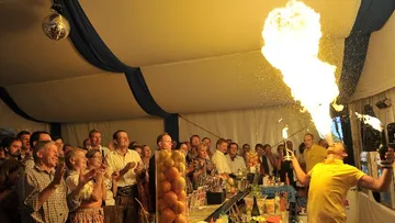 Ein Barkeeper speit Feuer, während Zuschauer begeistert klatschen.