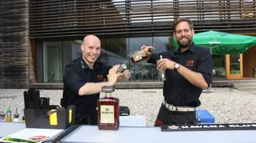 Zwei Barkeeper mixen Cocktails an einer Außenbar.