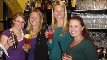 Vier Frauen halten Cocktails in einer Bar.
