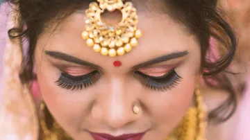 Woman with jewelry looks down, wearing makeup and elegant.