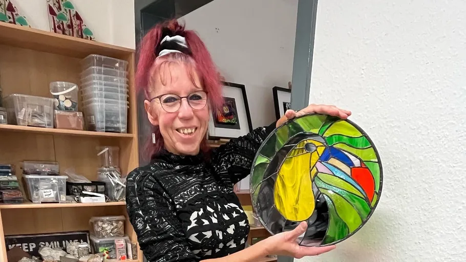 Person, die im Haus bunte Glasmalereien hält.