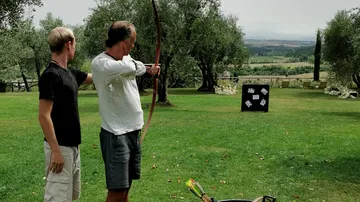 A man aims a bow at a target.