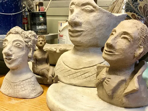 Sculptures stand on a table in a studio.