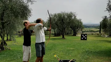 Two people shoot at targets with bows and arrows.