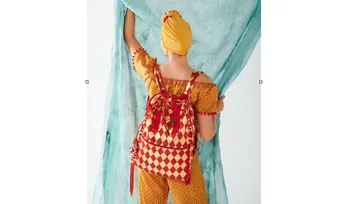 Person with colorful outfit opens a turquoise curtain.