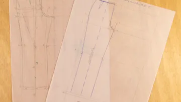 Zwei Schnittmuster für Hosen liegen auf einem Tisch.