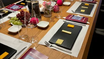 Tisch gedeckt mit Käse, Trauben und Gläsern für Gäste.