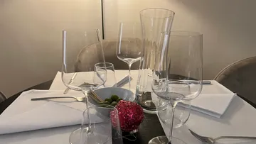 Tisch gedeckt mit Gläsern, Oliven und einem Dekorationsobjekt.