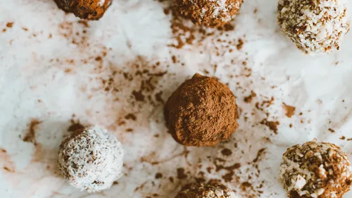 Schokoladenkugeln liegen auf weißem Papier verstreut.