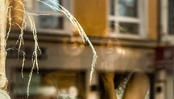 Spiegelnde Fenster zeigen lächelnde Personen im Hintergrund.
