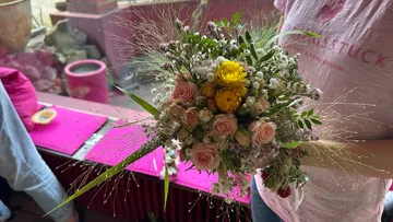Bouquet of flowers is held surrounded by pink and green decoration.