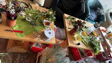 Two tables with floral arrangements and craft materials.