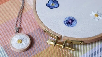 Handmade embroidery and necklace on colorful background.