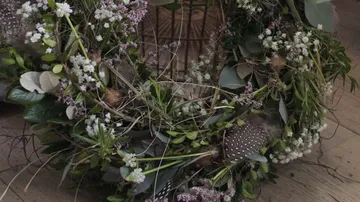 Kranz aus Pflanzen und Blumen auf einem Holzboden.