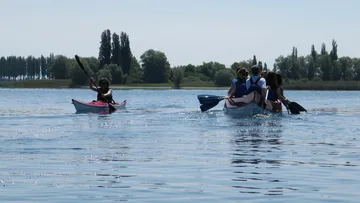 Eine Person paddelt im Kajak, während andere boote fahren.