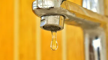 Ein Wasserhahn tropft über einer glatten Oberfläche.