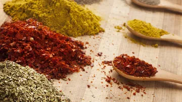 Spices are scattered on a wooden board.